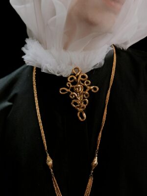 Close-up of a model wearing a veil and gold jewelry, exuding elegance and mystery.