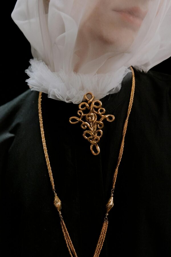 Close-up of a model wearing a veil and gold jewelry, exuding elegance and mystery.