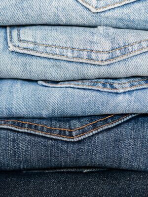 Closeup of stack of blue denim pants neatly arranged according to color from lightest to darkest