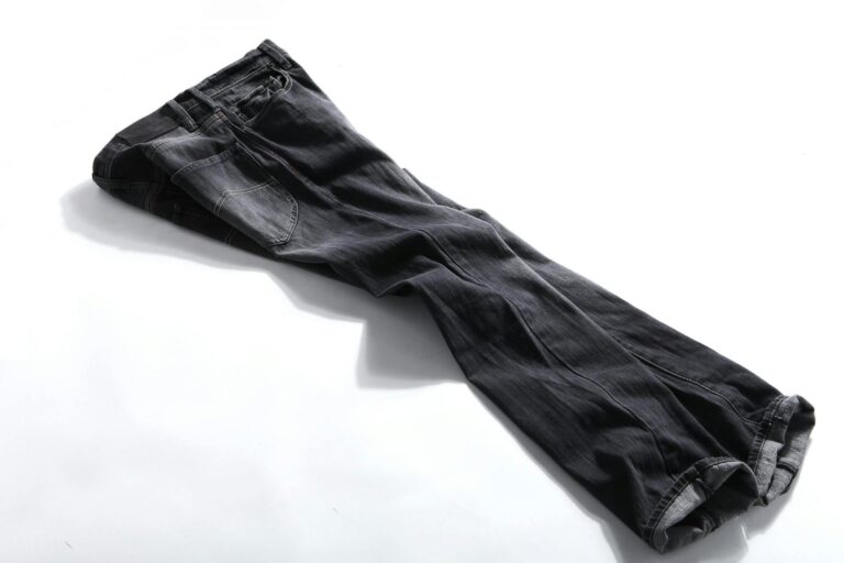 High-quality photo of neatly folded dark denim pants on a white background, showcasing fashion details.