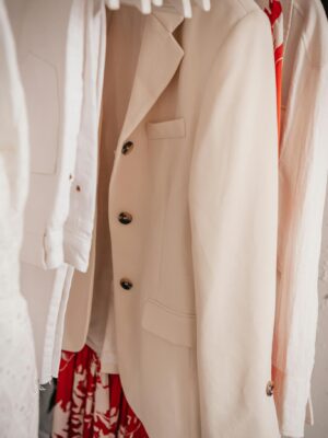 Stylish beige suit jacket hanging in a modern wardrobe with vibrant clothing.