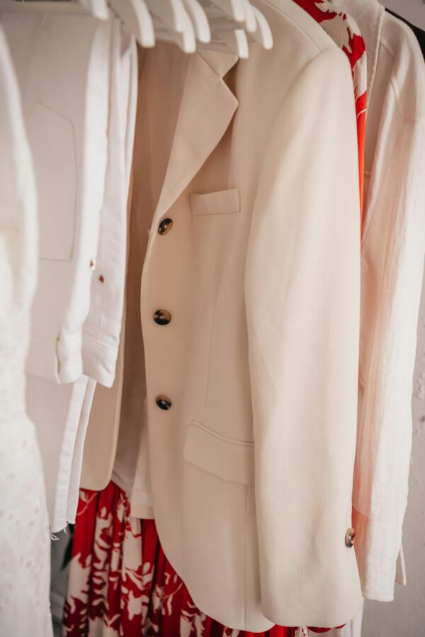 Stylish beige suit jacket hanging in a modern wardrobe with vibrant clothing.