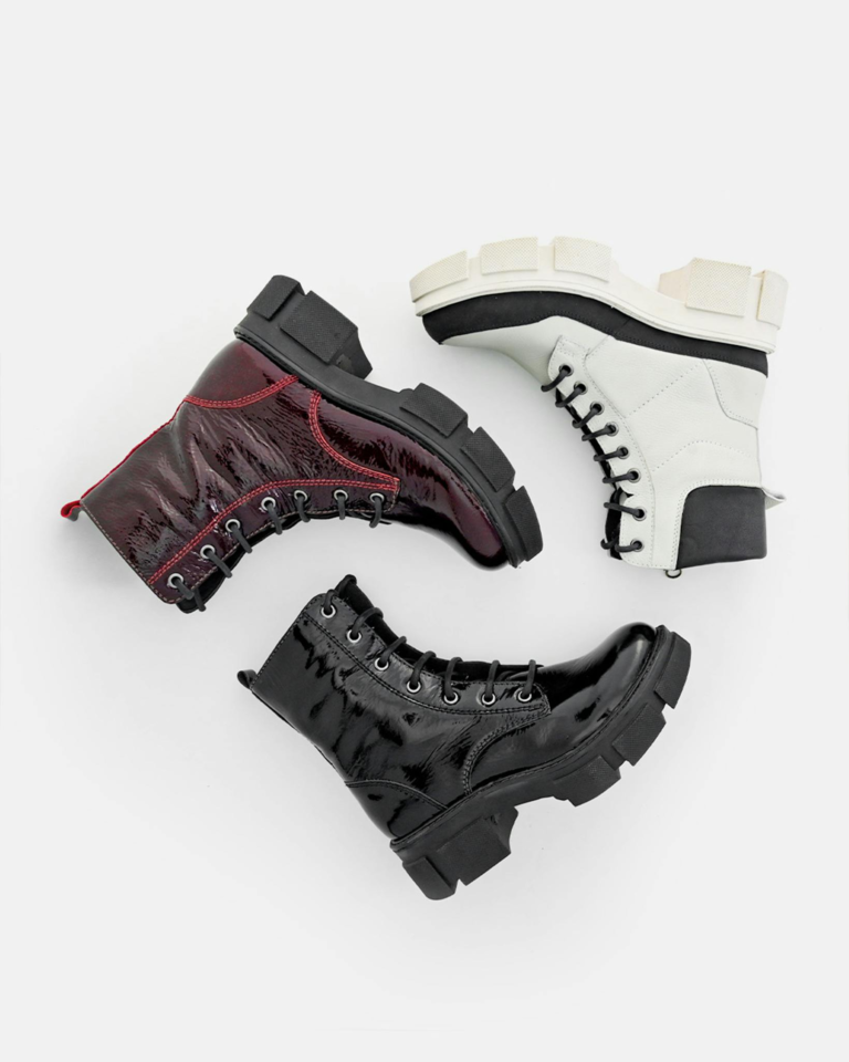 Stylish leather lace-up boots in black, white, and red on a white background.